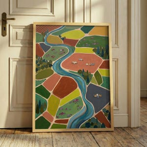 May include: A framed art print featuring an aerial landscape painting of a winding blue river flowing through patchwork fields in shades of green, brown, yellow, and gray, with small illustrated cats scattered across the terrain.