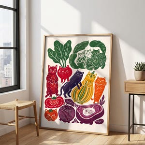 May include: A framed art print featuring a whimsical illustration of various cats integrated with vegetables and fruits. The design includes cats shaped like tomatoes, a beet, a dark purple onion, a yellow squash, and leafy green tops.