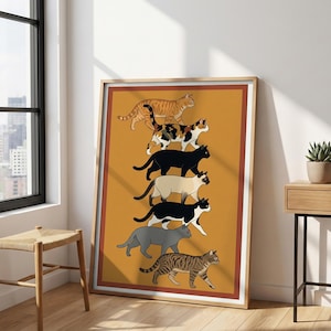 May include: A framed art print featuring a stack of seven stylized cats in various colors and patterns. The cats are depicted in a walking pose against a mustard-yellow background. The artwork is framed in a light wood-tone frame.