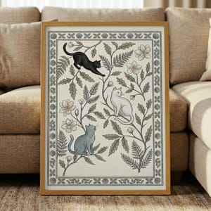 May include: A framed art print featuring three cats amidst floral and botanical elements. The cats are black, white, and blue, set against a cream background with a decorative border. The artwork is in a wooden frame.