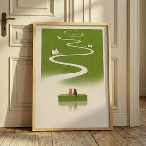 May include: A framed art print featuring a whimsical illustration of two cats, one orange and one black, sitting on a green bench. A winding white path leads through a green landscape, with trees and benches along the way. The artwork is in a wooden frame.