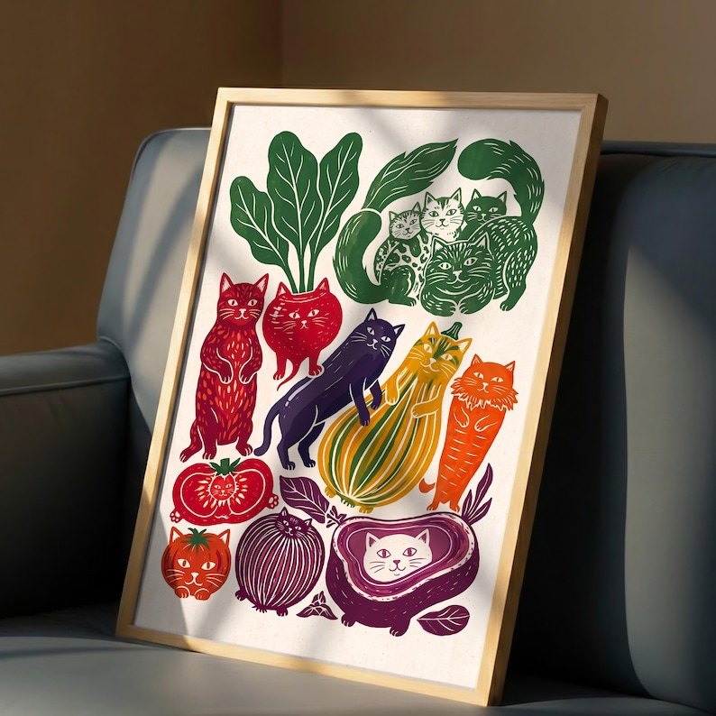 May include: A framed art print featuring a whimsical illustration of various cats integrated with colorful vegetables and fruits, including red tomatoes, a purple onion, a yellow squash, and green leafy greens on a white background.