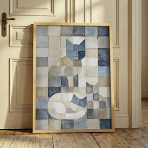 May include: A framed artwork featuring two stylized cats against a checkered background. The cats are depicted in shades of blue, gray, and beige, with a gold frame. The artwork is displayed against a neutral-toned wall and wooden floor.