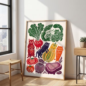 Pode incluir: Uma impressão artística emoldurada apresentando uma ilustração caprichosa de vários gatos integrados com frutas e vegetais coloridos, incluindo tomates vermelhos, uma cebola roxa, uma abóbora amarela e folhas verdes sobre um fundo creme.