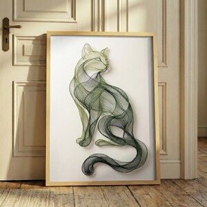 Könnte beinhalten: Gerahmtes Kunstwerk mit einer stilisierten Katzensilhouette. Die Katze wird mit fließenden grünen und schwarzen Linien vor einem weißen Hintergrund dargestellt. Der Rahmen besteht aus hellem Holz, und das Kunstwerk lehnt an einer Tür.