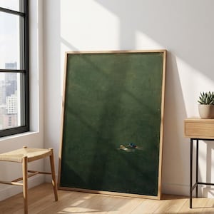 Pode incluir: Uma grande peça de arte emoldurada de formato retangular com um fundo verde floresta profundo e duas pequenas figuras a nadar no canto inferior direito. A moldura é de madeira clara e a obra retrata uma vasta superfície de água escura.