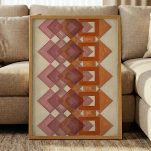 May include: A framed vertical wall art piece featuring a repeating geometric pattern of overlapping squares and diamonds in shades of pink, deep purple, and burnt orange, set against a textured off-white background within a light wood frame.