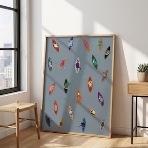 Op de afbeelding: Een ingelijst kunstwerk met kleurrijke kattenillustraties in kajaks op een grijze achtergrond. De kajaks hebben verschillende kleuren en de katten hebben verschillende patronen en kleuren. Het kunstwerk wordt tentoongesteld in een kamer met een raam en een houten kruk.