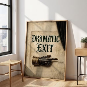 May include: A framed wall art print featuring a textured beige background with the dark green text "DRAMATIC EXIT" and a metallic, dark-toned gauntlet hand pointing to the right, positioned below the text with a black curtain on the right side.