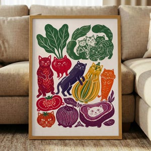 May include: A framed art print featuring a whimsical illustration of various cats integrated with vegetables and fruits, including a red cat, a purple cat, a yellow striped squash cat, and a white cat inside a purple eggplant shape.
