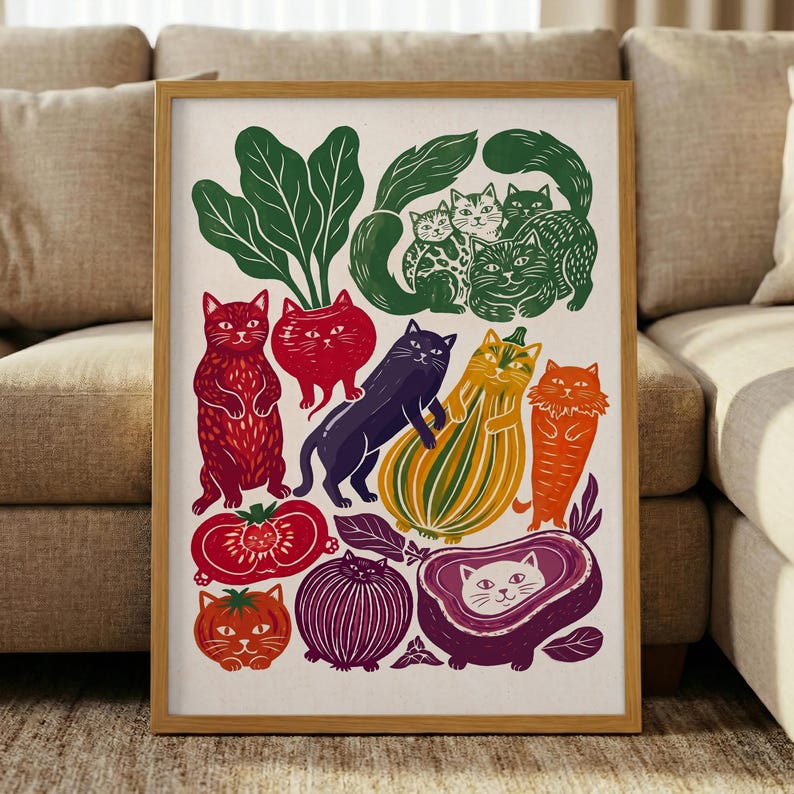 May include: A framed art print featuring a whimsical illustration of various cats integrated with vegetables and fruits, including a red cat, a purple cat, a yellow striped squash cat, and a white cat inside a purple eggplant shape.