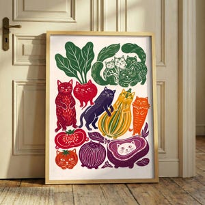 May include: A framed art print featuring a collection of stylized cats integrated with various vegetables and fruits. The illustration includes green leafy greens, red tomatoes, a purple onion, a striped squash, and a purple eggplant, all with cat faces.