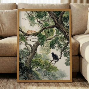 May include: A framed art print featuring a watercolor painting of two cats in a tree. One orange cat is curled up on a branch, while a black cat sits upright on another branch. The artwork has a natural, serene theme.