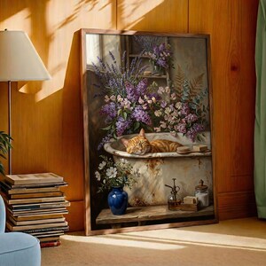 K&ouml;nnte beinhalten: Ein gerahmtes Kunstwerk zeigt eine rot getigerte Katze, die in einer Vintage-Badewanne voller Blumen schl&auml;ft. Das Gem&auml;lde hat einen Holzrahmen, eine blaue Vase und einen Stapel B&uuml;cher. Das Kunstwerk ist vor einer warmen Holzwand platziert.