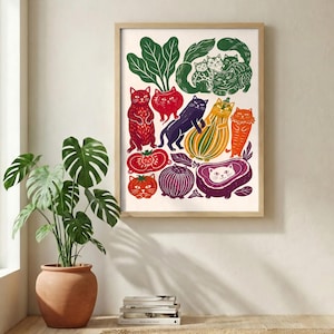 May include: A framed art print featuring a whimsical illustration of cats integrated with various vegetables. The artwork displays red, orange, yellow, purple, and green cats shaped like tomatoes, onions, squash, and leafy greens on a cream background.