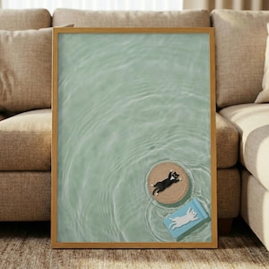 May include: A framed art print featuring a serene water scene with a light green hue. Two cat figurines are floating on the water: one black and white cat on a round, woven mat, and a white cat on a blue rectangle.