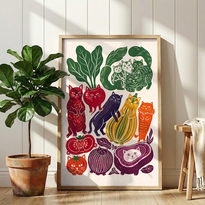 May include: A rectangular wall art print in a wooden frame featuring a colorful illustration of various cats integrated with vegetables and fruits, including red tomatoes, a purple onion, a yellow squash, and green leafy greens on a cream background.