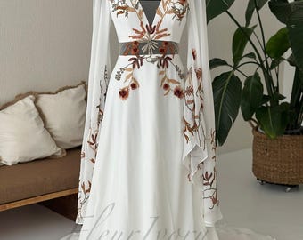 Vestido de novia bohemio de manga larga con bordado floral y escote en V profundo.