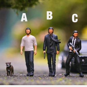 May include: Three miniature figures of a man wearing a black suit, a man wearing a grey shirt and a man wearing a black suit and holding a gun. The figures are standing on a grey surface. A small brown and white dog is standing in front of the figures.