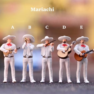 May include: A group of miniature Mariachi band figurines, all in white outfits with sombreros and red bow ties. The band members are playing instruments like guitars, a trumpet, and a violin. The word "Mariachi" is displayed above the band.