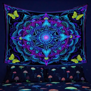 Puede incluir: Tapiz negro con un vibrante diseño de mandala brillante en tonos azules, morados y rosas. El tapiz presenta un patrón central de estrella y cuatro mariposas amarillas. También se muestra un juego de cama con diseños de hongos.