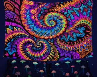 May include: A black tapestry with a psychedelic design featuring swirling patterns in shades of pink, blue, yellow, and orange. The tapestry is hanging on a wall above a bed with a matching mushroom print.