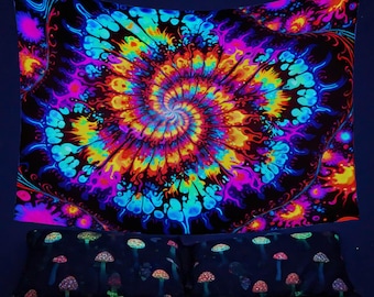 May include: A psychedelic tapestry with a colorful spiral design on a black background. The tapestry is hanging on a wall above a bed with a black and white mushroom print.