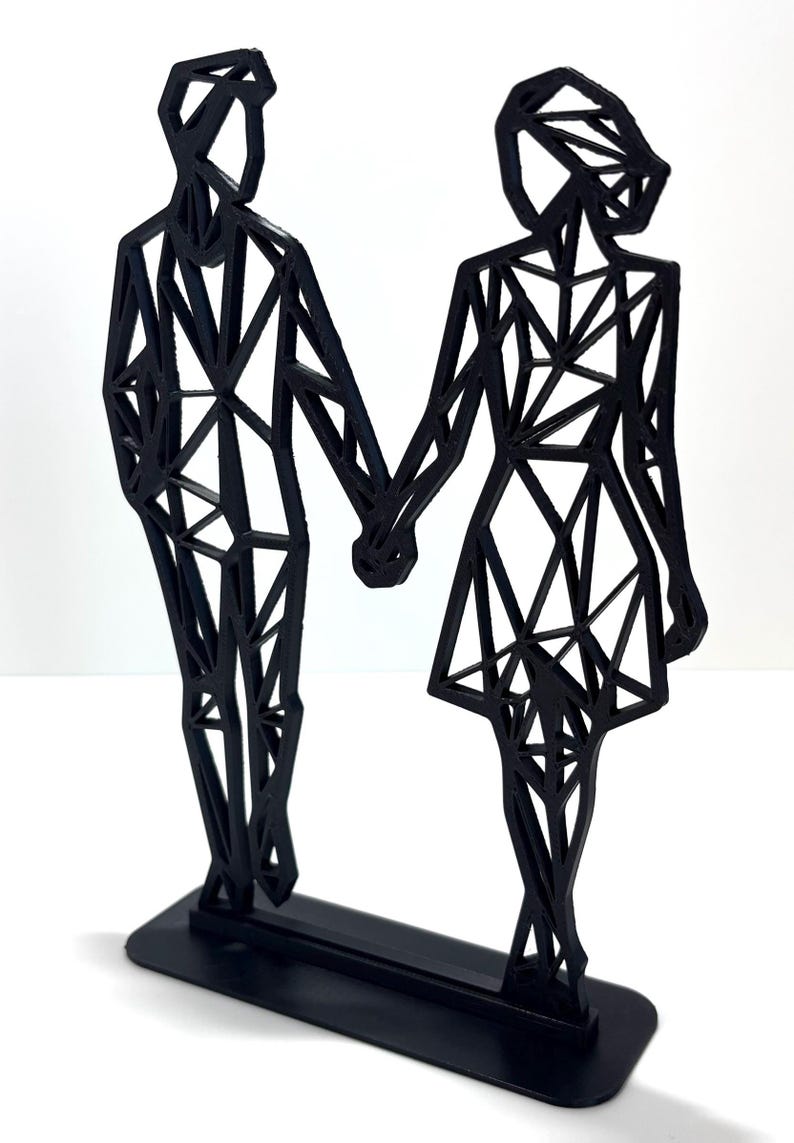 May include: Black geometric sculpture of a couple holding hands. The figures are stylized with angular shapes and stand on a rectangular base. A modern, minimalist design.