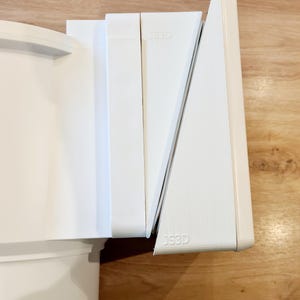 Könnte beinhalten: Weiße Eckregal-Einheit aus Kunststoff mit dem Aufdruck "JSSD" auf der Vorderseite. Die Regaleinheit besteht aus mehreren Teilen, die ineinander passen.