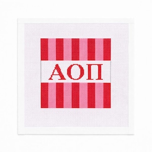 May include: A square canvas with a white border features a design with red and pink vertical stripes. The Greek letters ΑΟΠ are displayed in red on a white horizontal band, creating a bold and eye-catching pattern.