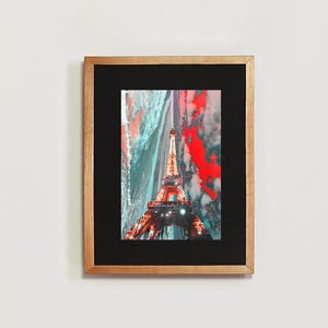 May include: A framed print of the Eiffel Tower in Paris, France. The tower is lit up at night and the sky is a mix of blue and red.
