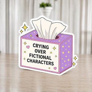 Könnte beinhalten: Ein Aufkleber mit einer lila Taschentuchbox mit dem Text "Crying Over Fictional Characters". Die Box hat einen rosa Rand, gelbe Sterne und Herzen. Weiße Taschentücher ragen aus der Oberseite heraus.