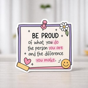 Op de afbeelding: Een sticker met een lichtbeige achtergrond en een paarse rand. De sticker bevat de woorden "BE PROUD" en een motiverende boodschap. Het bevat een roze punaise, een madeliefje, een hart, een smiley en decoratieve sterren.