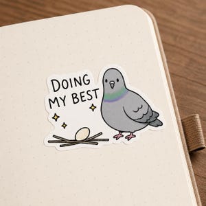 May include: A sticker featuring a cartoon pigeon with the text "DOING MY BEST." The pigeon is gray with a green and purple neck, standing next to a nest with an egg. Four yellow stars surround the text.