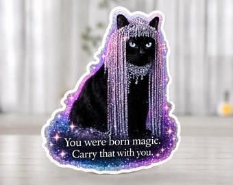 Könnte beinhalten: Ein gestanzter Aufkleber mit einer schwarzen Katze, die einen schimmernden lila-silbernen Fransen-Kopfschmuck trägt. Die Katze sitzt auf einer Basis im Galaxie-Design mit dem Text, You were born magic. Carry that with you. Mit Sternakzenten.