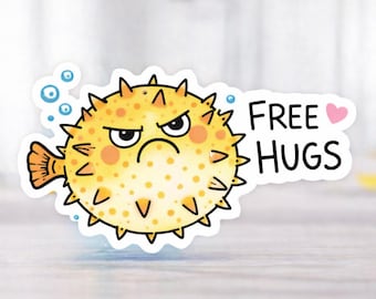 Könnte beinhalten: Ein Aufkleber mit einem Cartoon-Kugelfisch mit einem wütenden Gesichtsausdruck. Der Fisch ist gelb mit orangefarbenen Punkten und schwarzen Stacheln. Der Text "FREE HUGS" erscheint mit einem rosa Herz.