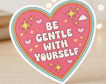 Puede incluir: Una pegatina en forma de corazón con fondo rosa que presenta el texto BE GENTLE WITH YOURSELF en letras blancas. El diseño incluye estrellas amarillas, pequeños corazones rosas y una nube blanca, enmarcados por bordes concéntricos en azul verdoso y naranja.