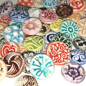 May include: Assortment of colorful ceramic buttons with various patterns and designs. The buttons are round and have a hole in the center.