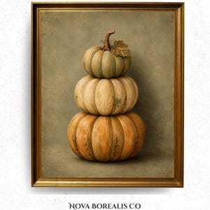 Puede incluir: Una lámina de arte enmarcada que muestra una pila vertical de tres calabazas en tonos apagados de verde, crema y naranja. La calabaza superior tiene un pequeño tallo y una hoja. La obra de arte está dentro de un marco dorado sencillo.