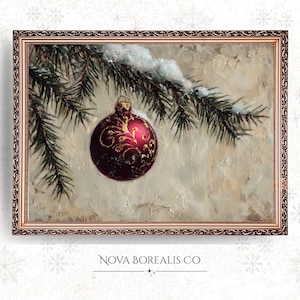 Peut inclure: Peinture encadrée d'une décoration de Noël. L'ornement est rouge foncé avec des motifs dorés, suspendu à une branche de conifère enneigée. Le tableau a un fond texturé blanc cassé et un cadre doré décoratif. Le texte "NOVA BOREALIS CO" est en bas.