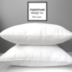 Puede incluir: Dos insertos de almohada blancos apilados uno encima del otro sobre un fondo gris. El inserto de almohada superior tiene una etiqueta blanca con el texto "mazizmuse design co. Pillow Insert".