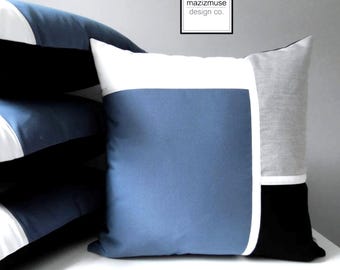 Funda de almohada para exteriores Sunbrella® en azul zafiro y gris con bloques de color blanco y negro, cojines azules y grises para tumbonas de patio o piscina.