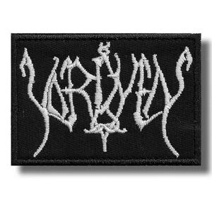 May include: Black rectangular patch with white embroidered gothic lettering. The patch has a black border and a white embroidered design in the center. The design is a stylized word or symbol, likely for a band or brand.
