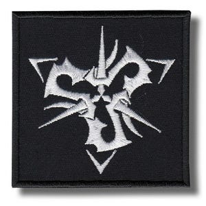 May include: Black square patch with a white, intricate emblem. The emblem has a central design with sharp, angular shapes and a symmetrical arrangement. The patch has a black border and is likely an embroidered patch.