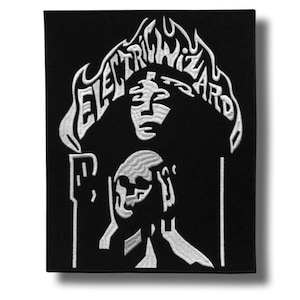 Könnte beinhalten: Schwarz-weißer Aufnäher mit dem Text "ELECTRIC WIZARD" in einer stilisierten Schriftart über einer Grafik eines Gesichts und eines Schädels. Der Aufnäher hat eine rechteckige Form.