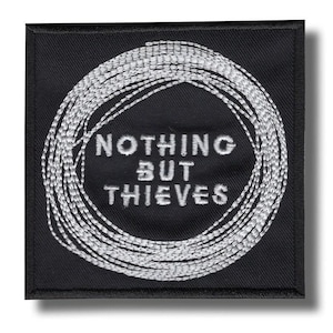 Może przedstawiać: Czarna kwadratowa naszywka z białym haftowanym tekstem i wzorem. Tekst brzmi "NOTHING BUT THIEVES" w okrągłym wzorze z białych linii. Naszywka ma czarną obwódkę i prawdopodobnie jest naszywką do naprasowywania lub przyszywania.