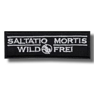 以下が含まれることがあります： 白の刺繍文字が入った長方形の黒いパッチ。テキストは「SALTATIO MORTIS」と「WILD」と「FREI」の上にあり、中央に円形のエンブレムがあります。パッチは衣類やアクセサリー用です。