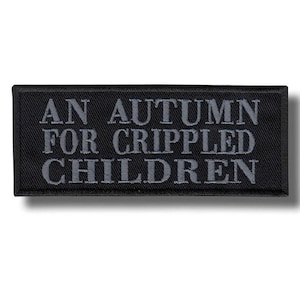 Puede incluir: Parche rectangular negro con el texto "AN AUTUMN FOR CRIPPLED CHILDREN" bordado en gris. El parche tiene un borde negro y probablemente está diseñado para ser cosido o adherido a ropa o accesorios.