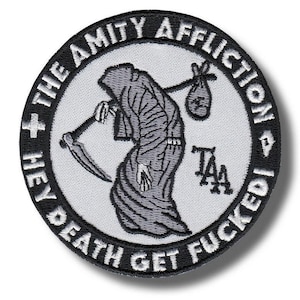 Könnte beinhalten: Ein runder Aufnäher mit dem Text "HEY DEATH GET FUCKED!" und "THE AMITY AFFLICTION" in weißer Schrift auf einem schwarzen Rand. Der Aufnäher zeigt eine graue Sensenmann-Figur mit einer Sense und einem Sack.