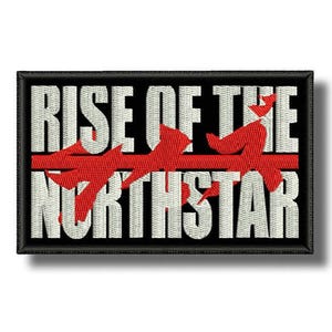 May include: Embroidered patch featuring the text "RISE OF THE NORTHSTAR" in white block letters on a black background. A red line and stylized red shapes cross the text. The patch has a black border.